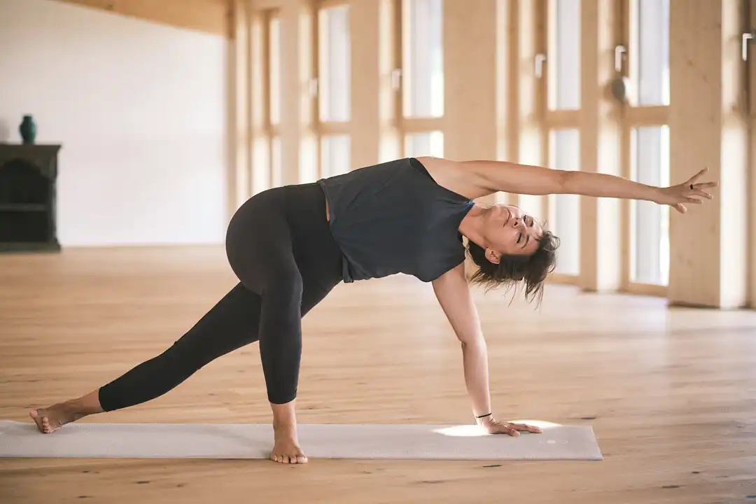 Yoga mit Weitblick im Hofgut Wagrain – kraftvolle Dehnung und innere Balance im lichtdurchfluteten Bewegungsraum aus Naturholz.