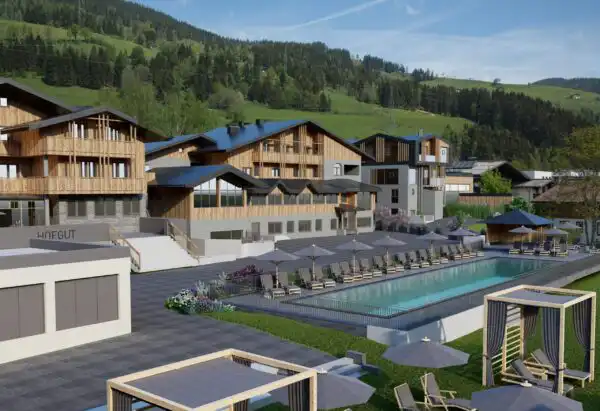 Modern outdoor pool with loungers in the alpine lifestyle resort Hofgut Wagrain, surrounded by stylish flats and mountain scenery in summer.
