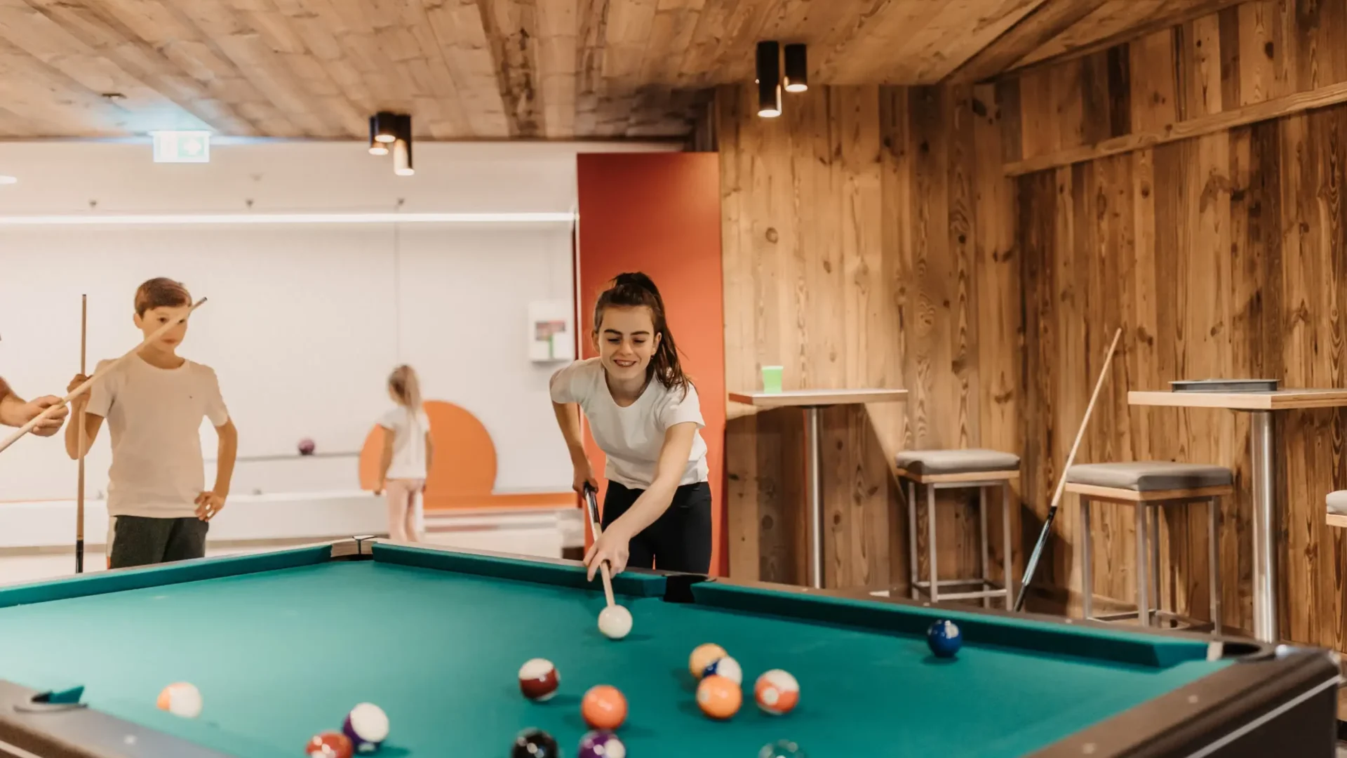 Spielspaß für Groß und Klein: Familienzeit am Billardtisch in der stylischen Games Area des Hofgut Wagrain – gemeinsam lachen, zielen und genießen.
