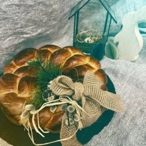 Gyldenbrun bagt påskeflette, festligt dekoreret med naturmaterialer - en kærlig påskehilsen fra Hofgut-bageriet fuld af varme, tradition og glæde.