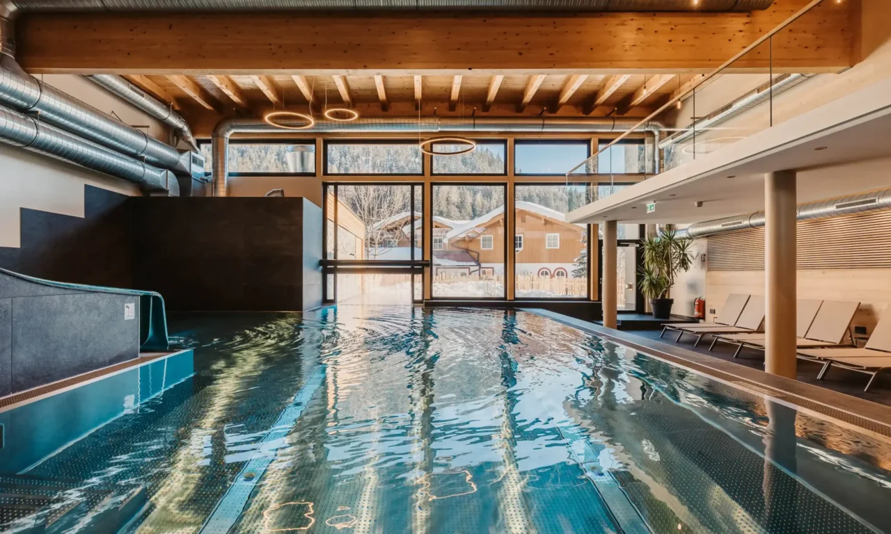 Stemningsbillede af den indendørs pool på Hofgut Wagrain med udsigt over den snedækkede dal - hyggelig varme, moderne design og et unikt sted at stoppe op et øjeblik.