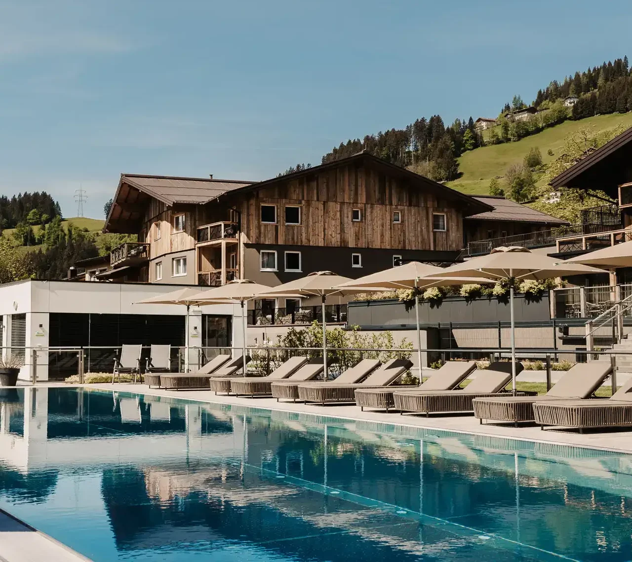 25-Meter-Sportbecken im Hofgut Wagrain mit Sonnenliegen und Schirmen – Sommerliche Ruheoase mit Bergblick für aktive und entspannte Urlaubstage im Salzburger Land.