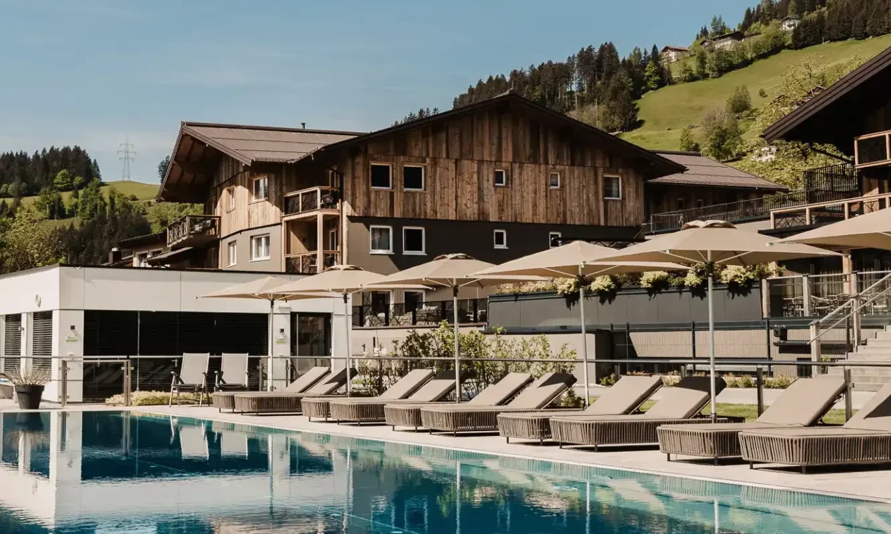 Hofgut-Wagrain-Apartment-Lifestyle-Resort-Wagrain 416-Sportpool-Sommer 25-Meter-Sportbecken im Hofgut Wagrain mit Sonnenliegen und Schirmen – Sommerliche Ruheoase mit Bergblick für aktive und entspannte Urlaubstage im Salzburger Land.
