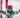 A smiling child wearing a pink helmet and Atomic skis sits in the snow and enjoys the winter day.