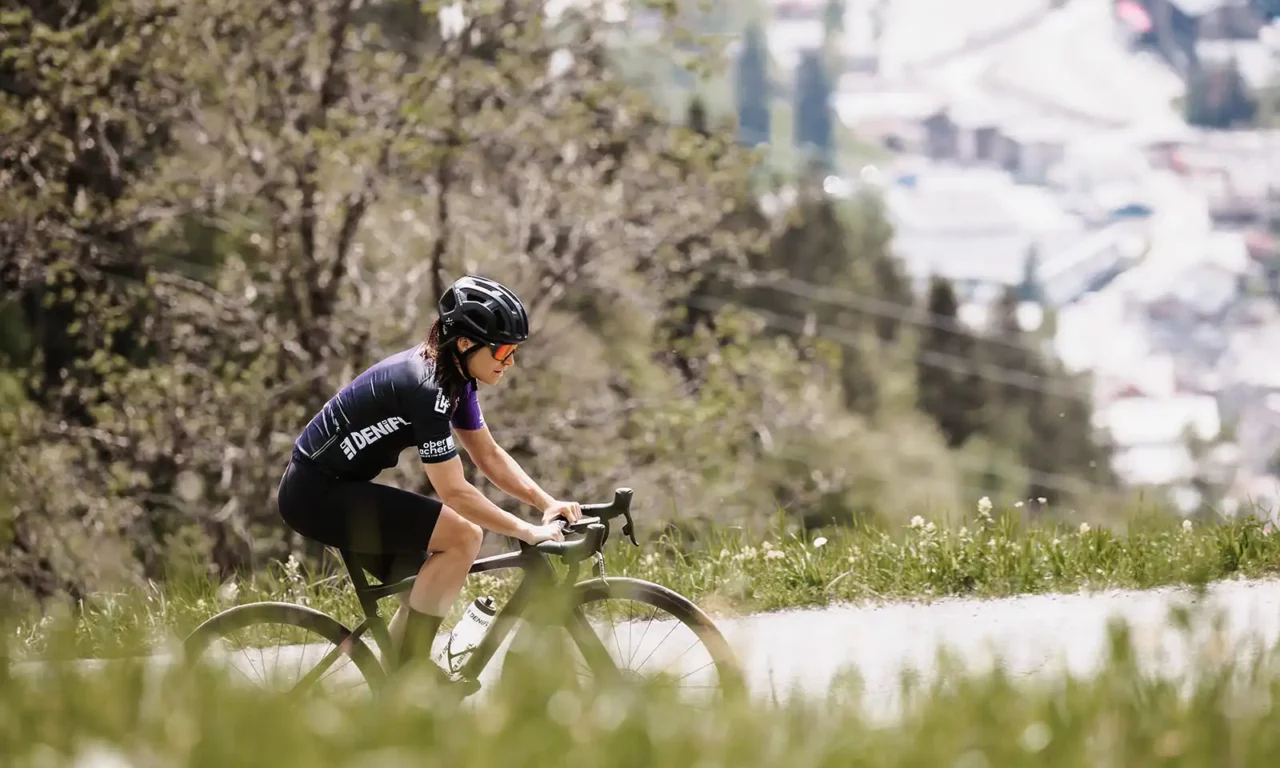 Hofgut©Elisabeth_Fotografie-11-Frau-Rennrad-Seitenansicht-Bergstraße-Wiese-Sonnenbrille-Apartment_&_Lifestyle_Resort_ Radfahrerin mit Sonnenbrille auf Bergstraße.