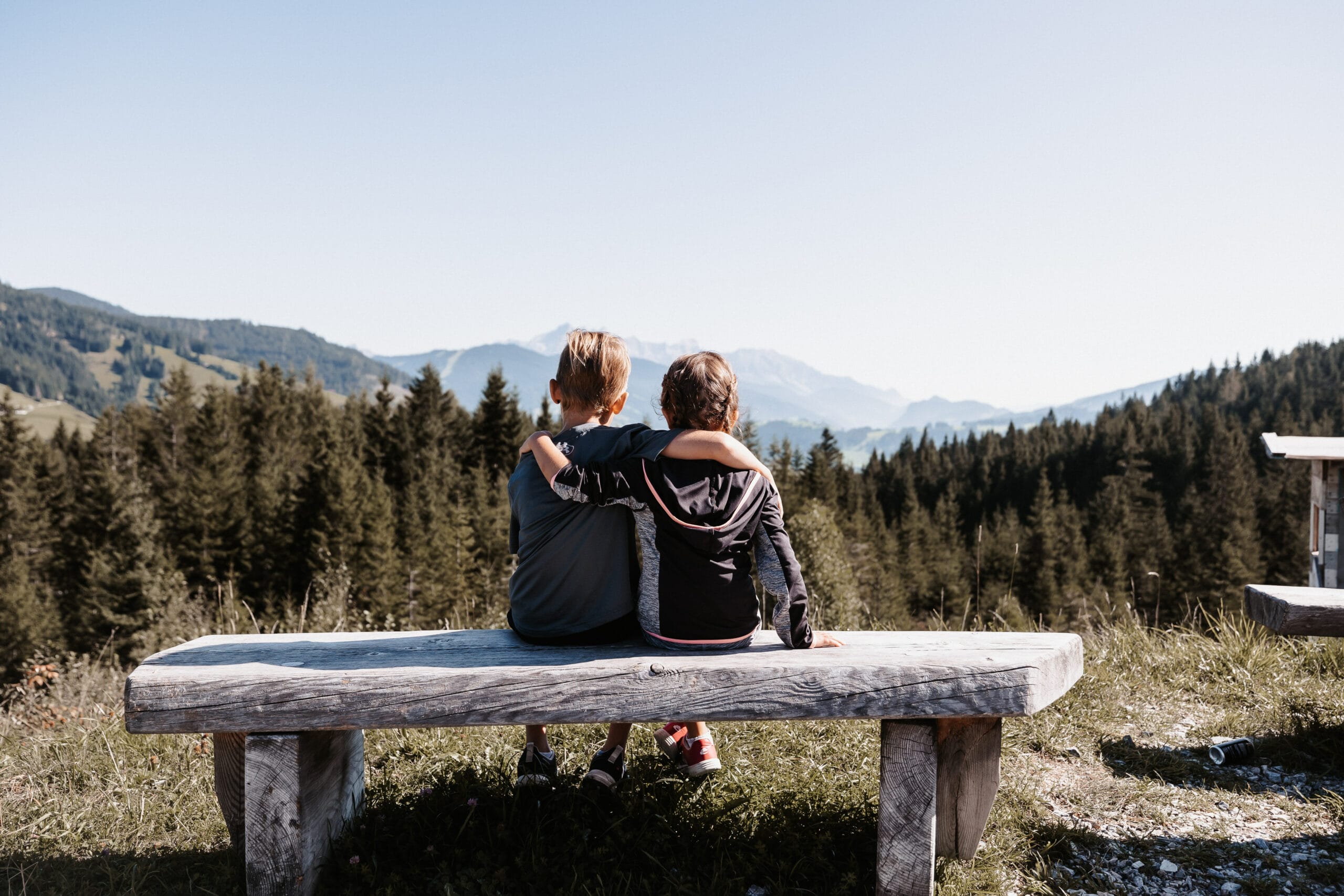 Zwei Kinder Arm in Arm mit Blick auf die Berge – Familienzeit im Hofgut Wagrain.