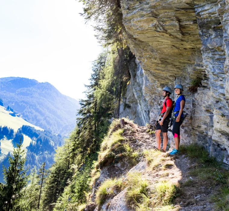 Two hikers on a via ferrata with mountain view