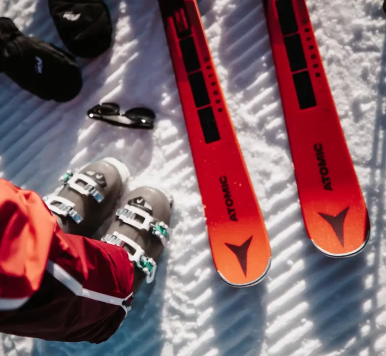 Close-up of ski boots and Atomic skis on the piste in the fresh snow.