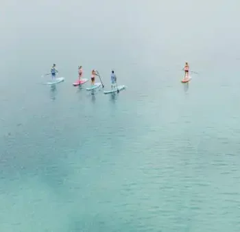 Stand-up paddling op turquoise blauw water - een gedeelde natuurervaring vol lichtheid en zomerplezier.