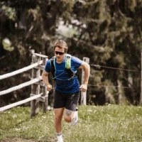 Trailrunning mit Weitblick – sportlicher Läufer beim energiegeladenen Anstieg auf einem Naturpfad rund um das Hofgut Wagrain, umgeben von grünen Wiesen und alpinem Flair.