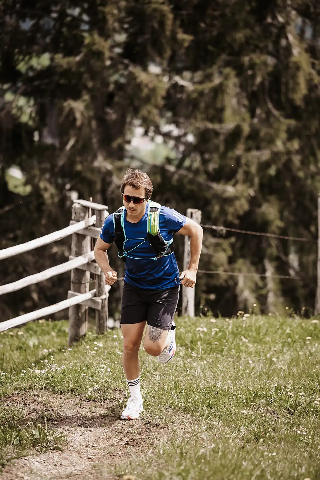 Trail running met uitzicht - sportieve hardlopers tijdens een energieke beklimming op een natuurpad rond Hofgut Wagrain, omgeven door groene weiden en alpiene flair.