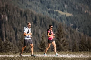 An active moment of pleasure in the mountains - sporty couple trail running along a high-altitude trail with fantastic views of the forests around Hofgut Wagrain.
