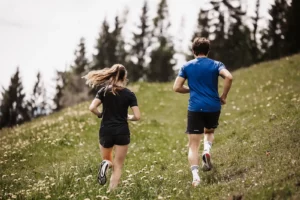 Running pleasure in the middle of nature - sporty couples run the trail through the flourishing meadows and forests around Hofgut Wagrain in Salzburger Land.