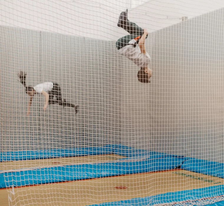Zwei Kinder springen auf Indoor-Trampolinen im Hofgut Wagrain, gesichert durch ein Netz.