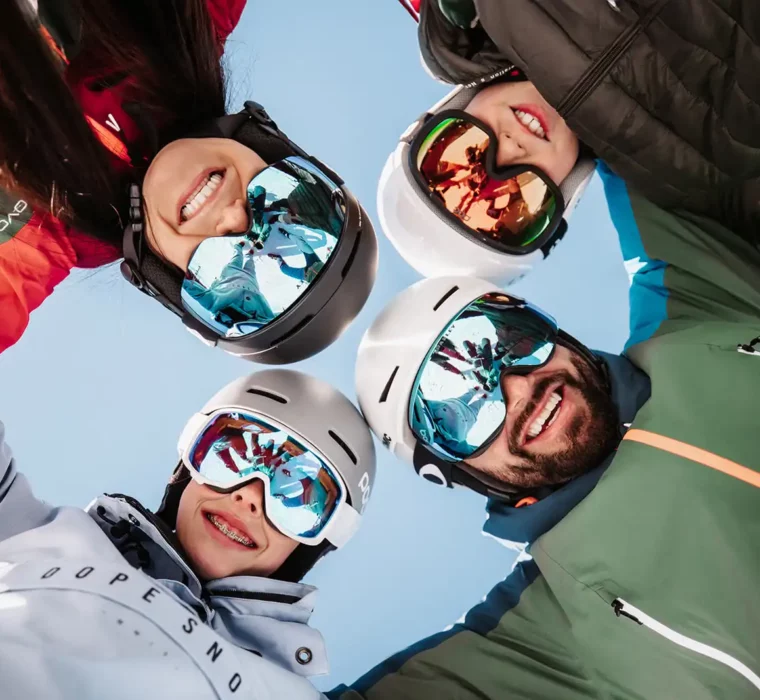 Family looks into the camera while skiing with ski helmets.
