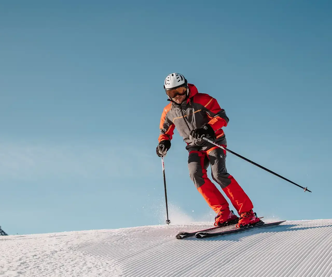 Skifahrer mit rotem Skianzug zieht Carving Schwünge auf perfekt Präparierten Pisten in Ski Amadè.
