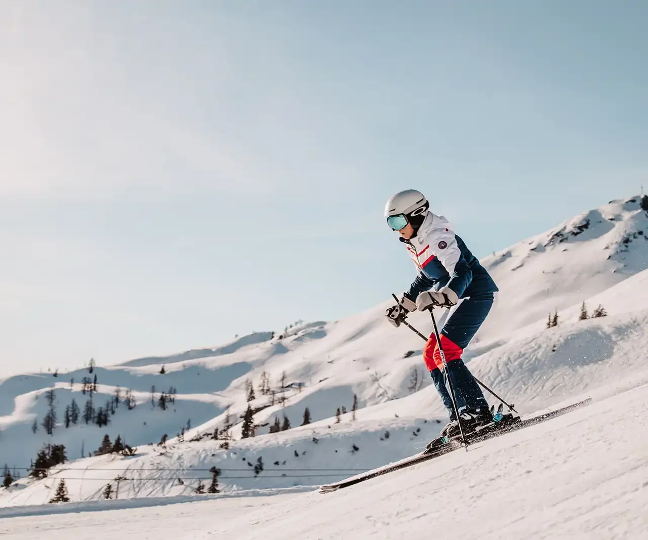 Skifahrerin fährt bei strahlenden Sonnenschein die Skipisten in Ski Amadè.