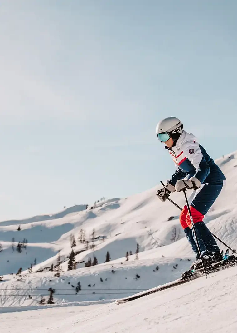 Skifahrerin fährt bei strahlenden Sonnenschein die Skipisten in Ski Amadè.