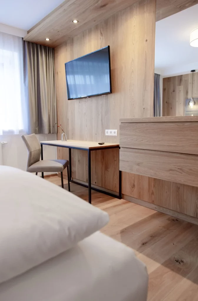 Hofgut-Wagrain-Apartment-Lifestyle-Resort-Freiheit-spueren-mit-Freunden-Apartment-Schlafraum- Modernes Apartmentzimmer im alpinen Design mit Schreibtisch und Flat-TV im Hofgut Wagrain