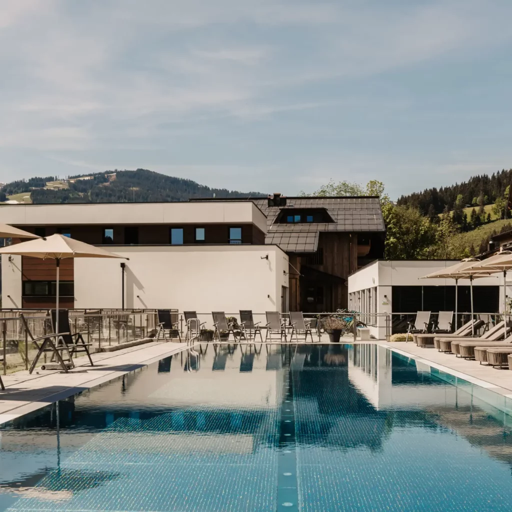 Hofgut-Wagrain-Apartment-Lifestyle-Resort-Wagrain 413 25-metre sports pool at Hofgut Wagrain with sun loungers and umbrellas - summer oasis of peace with mountain views for active and relaxing holidays in Salzburger Land.