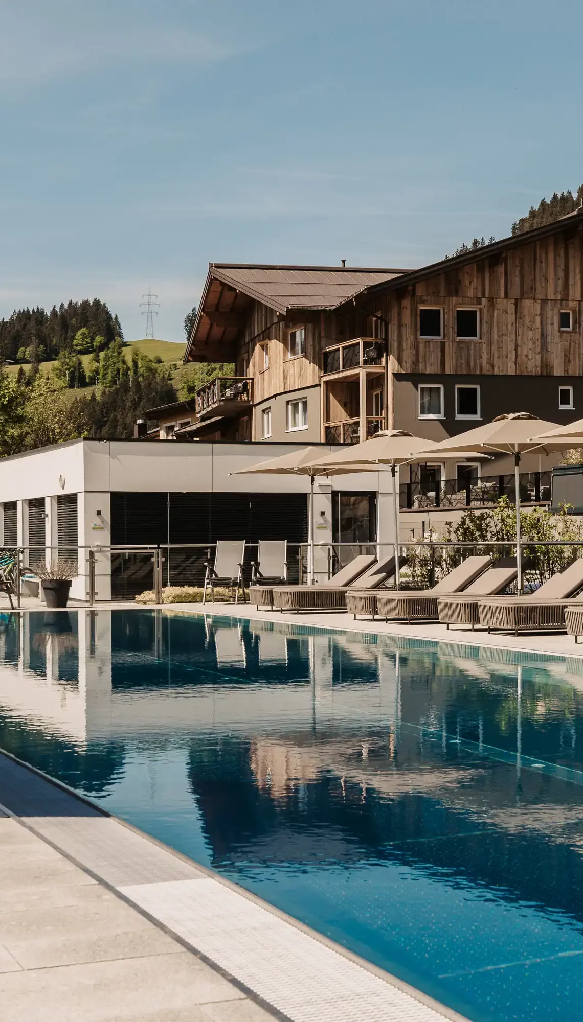 25-Meter-Sportbecken im Hofgut Wagrain mit Sonnenliegen und Schirmen – Sommerliche Ruheoase mit Bergblick für aktive und entspannte Urlaubstage im Salzburger Land.
