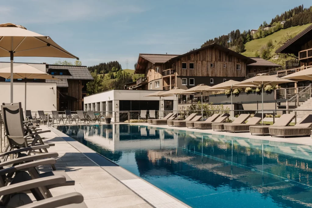 25-Meter-Sportbecken im Hofgut Wagrain mit Sonnenliegen und Schirmen – Sommerliche Ruheoase mit Bergblick für aktive und entspannte Urlaubstage im Salzburger Land.