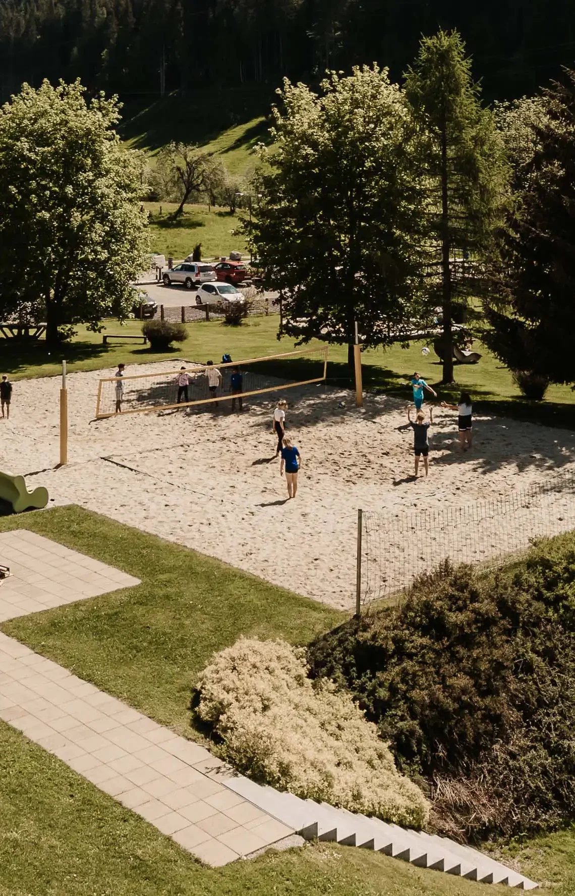 Gäste spielen Beachvolleyball im Hofgut Wagrain umgeben von Bäumen und Bergpanorama