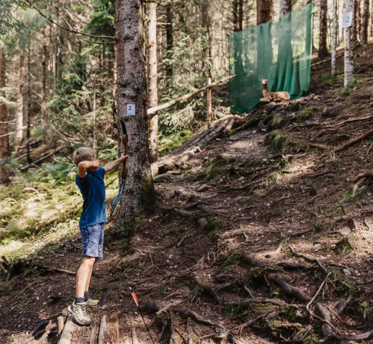 Hofgut-Wagrain-Apartment-Resort-Wagrain 515 Young boy practises archery on the 3D course in the forest near Hofgut Wagrain