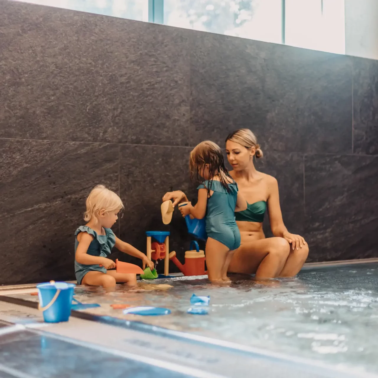 Hofgut-Wagrain-Apartment-Resort-Wagrain-Babypool 643 Playtime together in the baby pool - a mother and her two little daughters enjoy the relaxed atmosphere in the warm water area at Hofgut Wagrain, surrounded by loving details and child-friendly water toys.