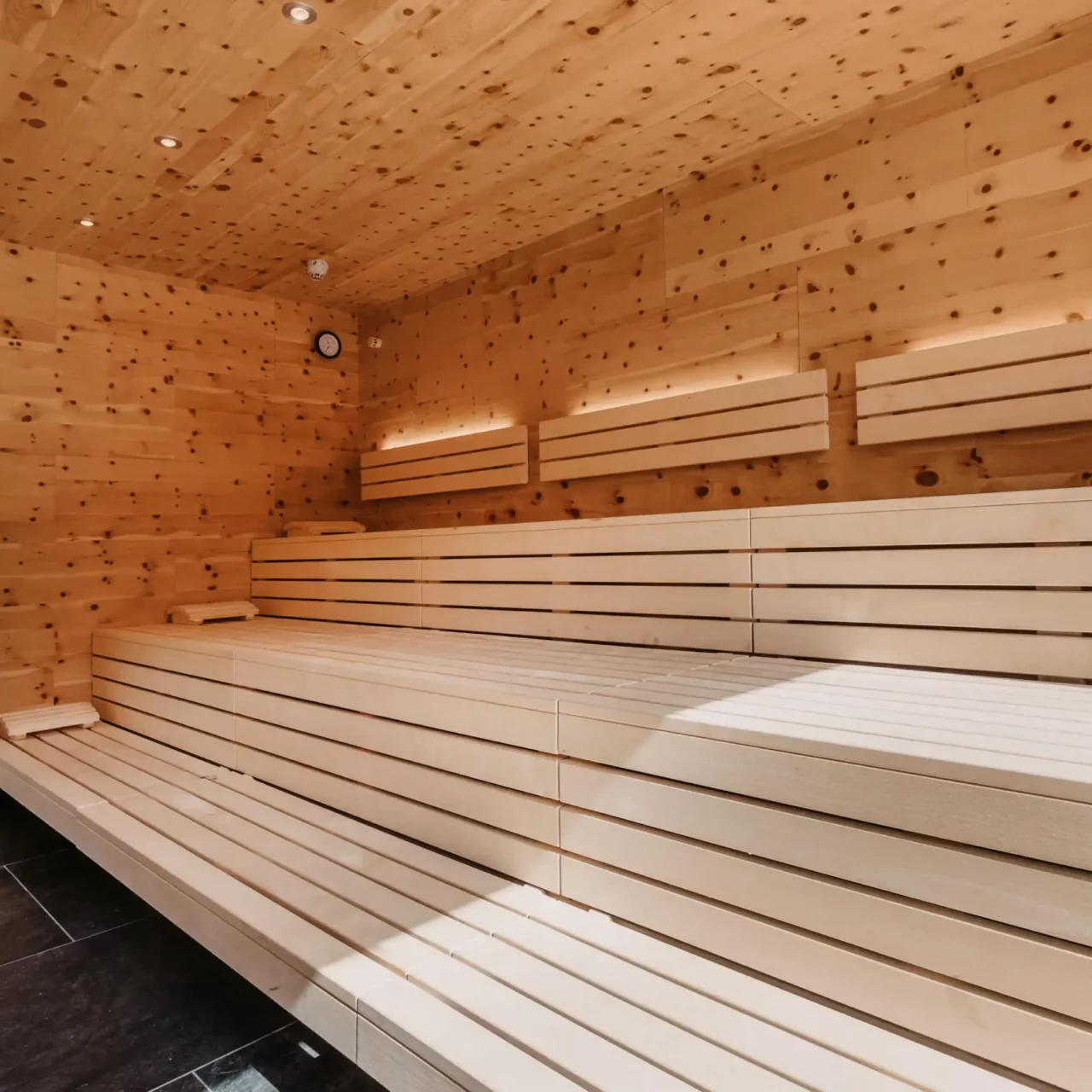 Světlá švýcarská kamenná borovicová sauna v Hofgut Wagrain - uklidňující teplo, voňavé švýcarské kamenné borové dřevo a moderní design pro relaxační chvíle pohody ve wellness centru určeném pouze pro dospělé.