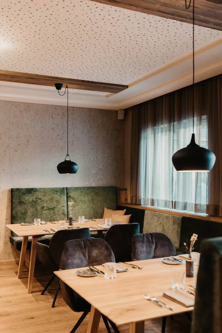 Cosy restaurant area at Hofgut Wagrain with stylish furnishings, soft upholstery and lovingly laid tables - an Alpine feel-good atmosphere to enjoy.
