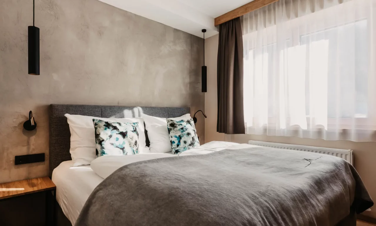 Hofgut-aparment-lifestyle-resort-wagrain-26 Gemütliches Schlafzimmer im Hofgut Wagrain mit modernem Boxspringbett, stilvollen Dekokissen und natürlichem Lichteinfall.