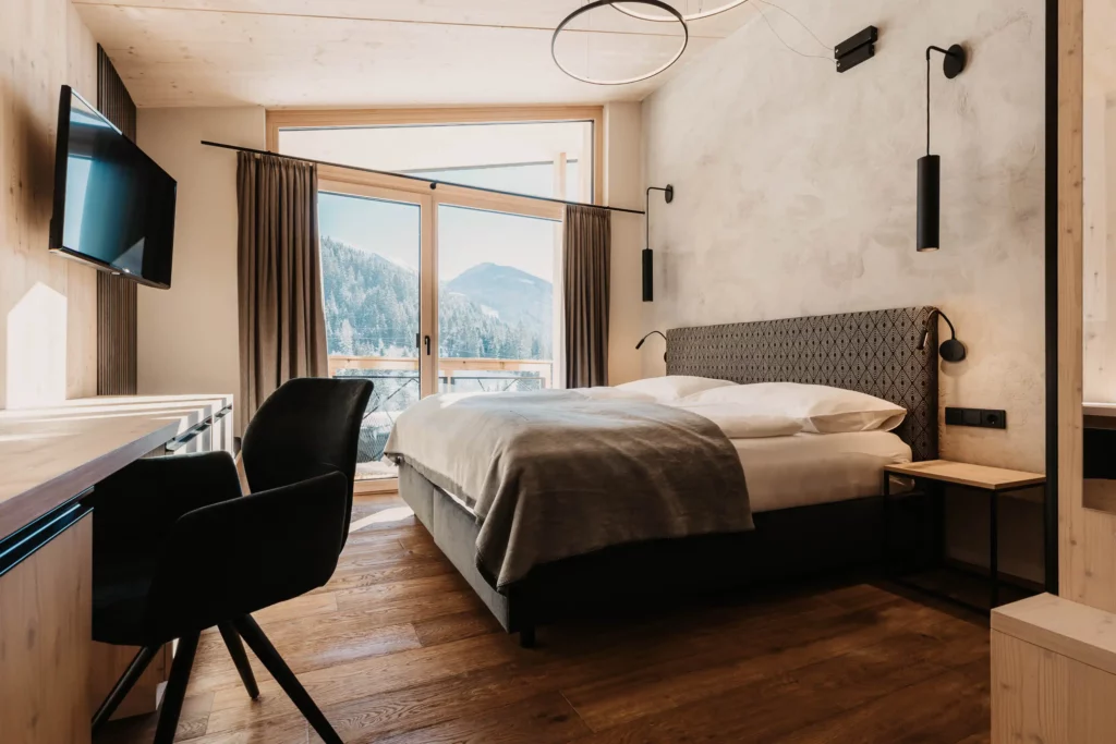 Alpine charm combines with modern design: a cosy bedroom with panoramic views and stylish details.
