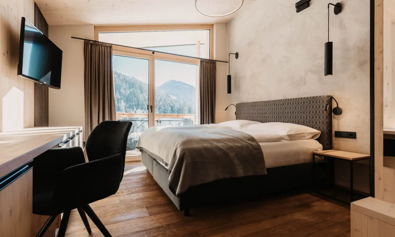 Alpine charm combines with modern design: a cosy bedroom with panoramic views and stylish details.