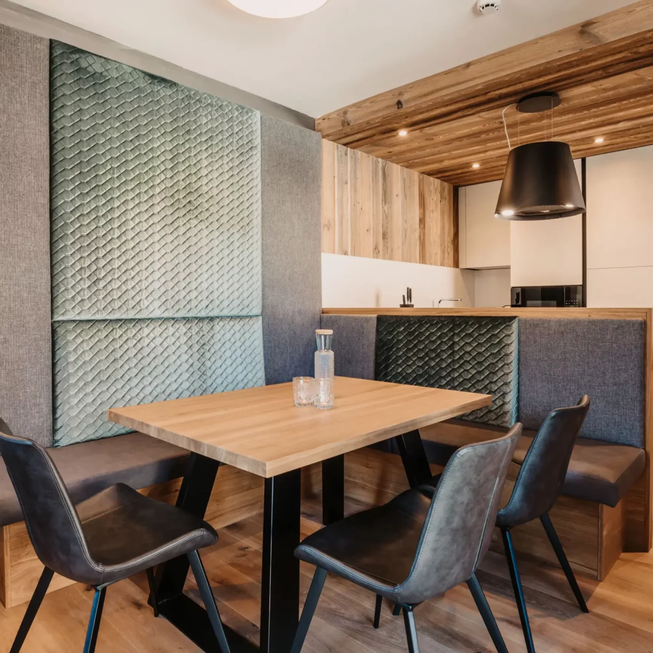 Gemütliche Ess- und Wohnküche im Hofgut Wagrain mit moderner Holzvertäfelung, stilvoller Sitzbank mit Rückenpolstern, elegantem Esstisch und stimmungsvollem Lichtdesign.