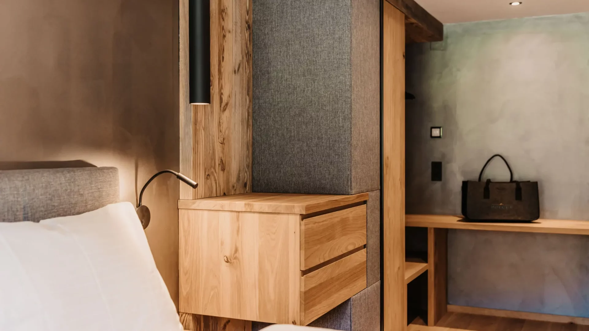 Close-up of the bedroom at Hofgut Wagrain with open wooden wardrobe, designer lamp and high-quality furnishings in Alpine style - stylish and functional at the same time.