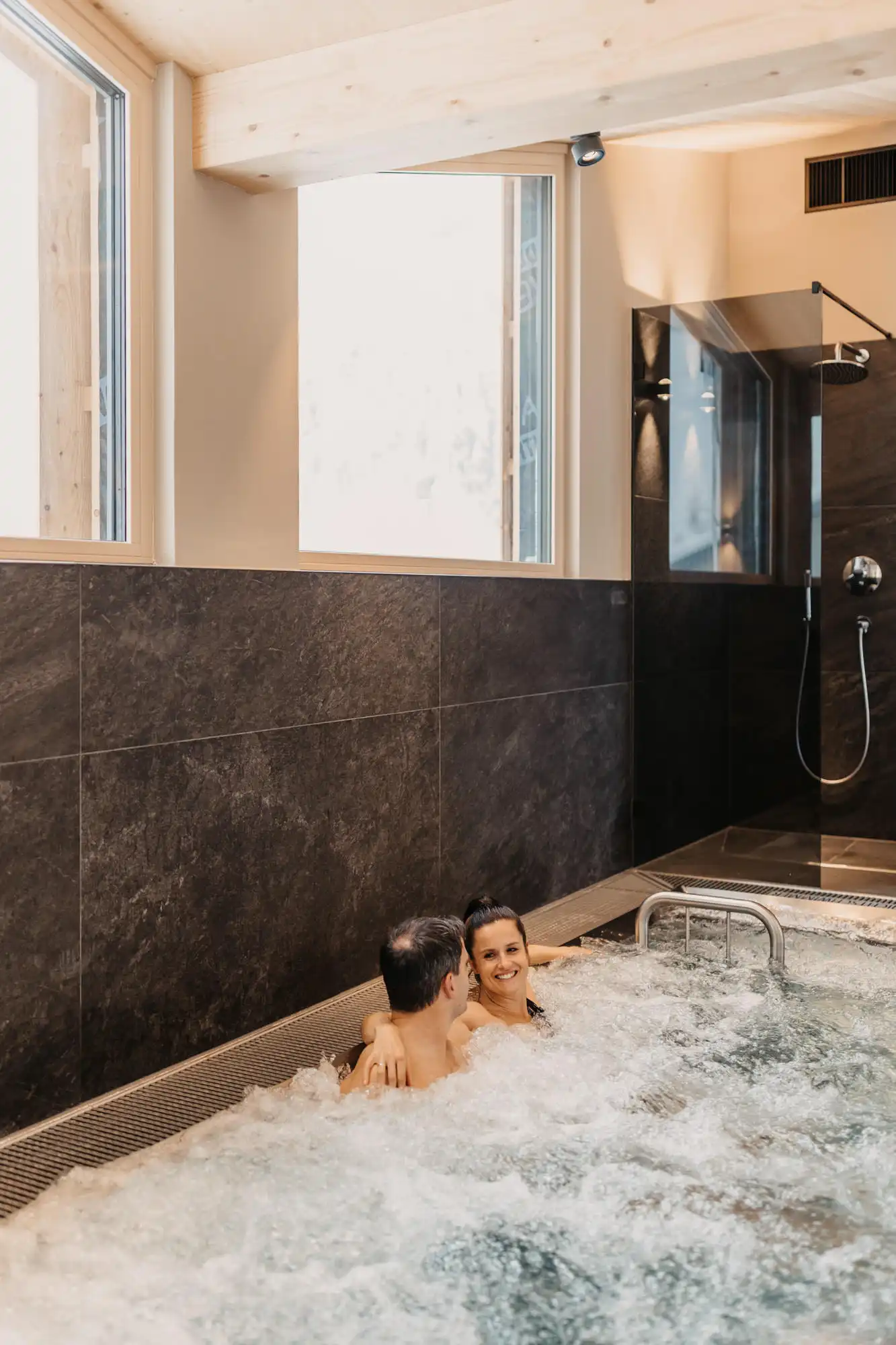 Hofgut-wagrain-apartment-280 Ein Paar entspannt sich im sprudelnden Whirlpool mit Blickkontakt – Wohlfühlmoment pur.