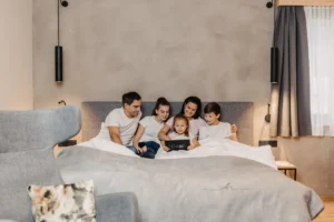 Gemeinsam kuscheln und lachen: Familienzeit im gemütlichen Bett der Hofgut-Apartments – perfekt für entspannte Urlaubsmomente mit allen Generationen.