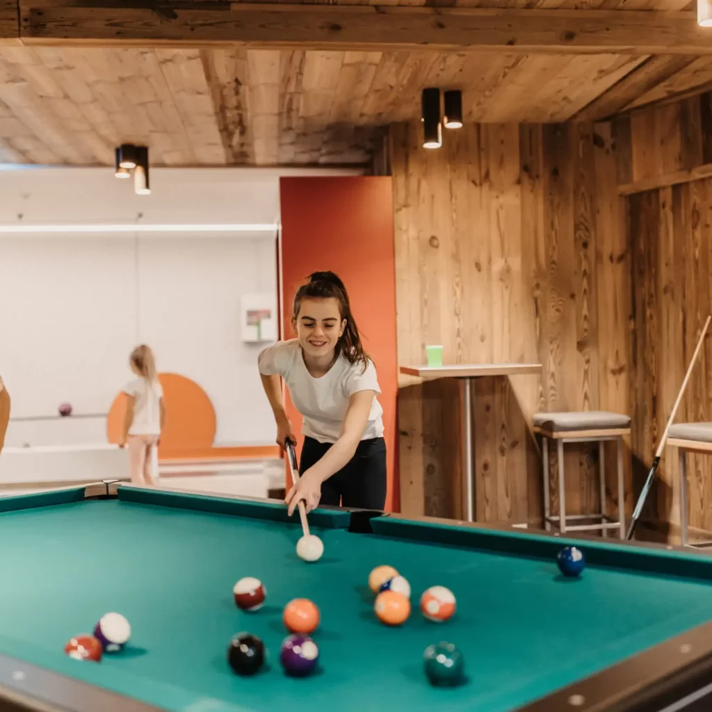 Hofgut-wagrain-apartment-66 Spielspaß für Groß und Klein: Familienzeit am Billardtisch in der stylischen Games Area des Hofgut Wagrain – gemeinsam lachen, zielen und genießen.