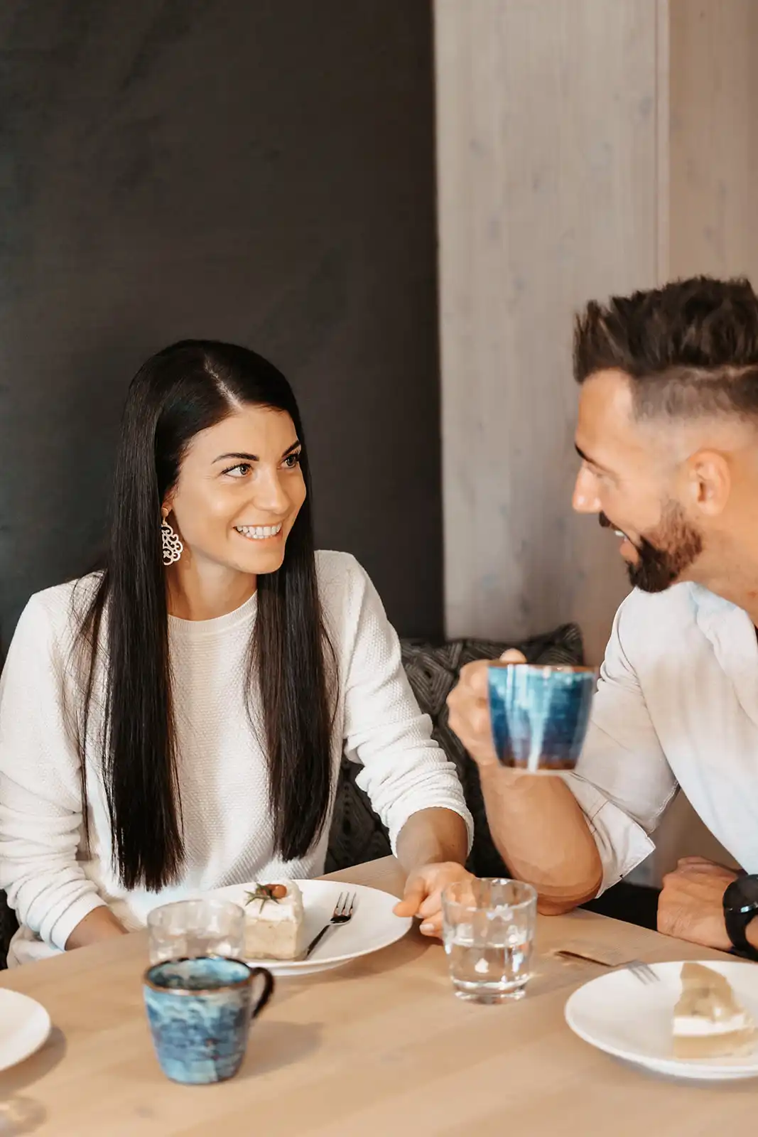 Hofgut©Elisabeth_Fotografie-392 Paar genießt Kaffee und Kuchen in stilvollem Ambiente, während sie sich liebevoll in die Augen sehen.