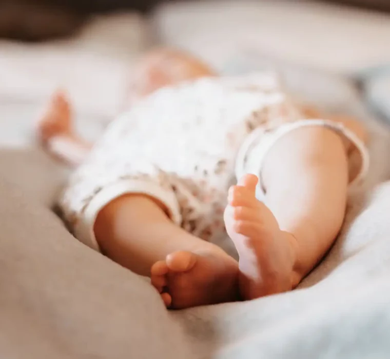 Baby lying relaxed on a cosy bed, surrounded by soft light - the perfect feel-good atmosphere for families with small children at Hofgut Wagrain.