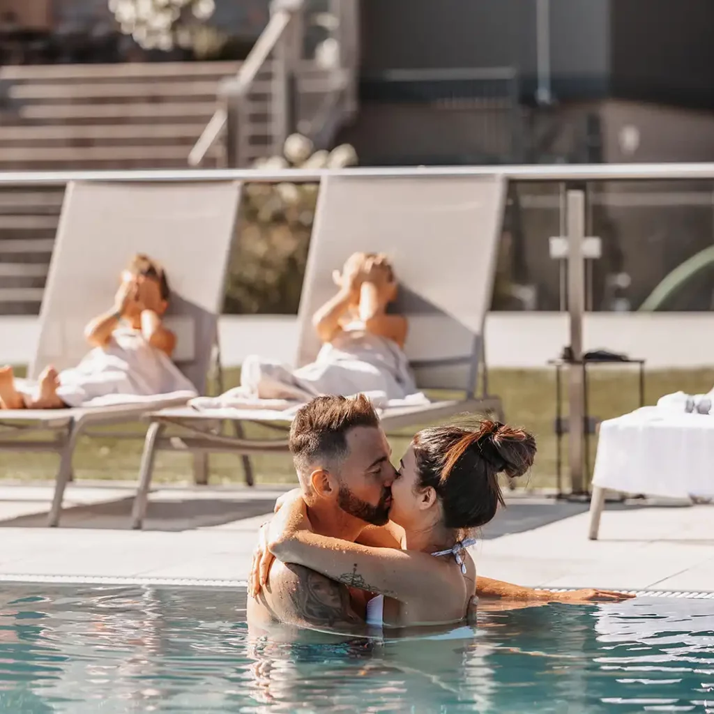 Hofgut©Elisabeth_Fotografie-580 Romantic moment on a family holiday - a couple enjoying intimate togetherness in the pool at Hofgut Wagrain while the children relax on the sun loungers. Holiday bliss for young and old in the midst of an Alpine idyll.