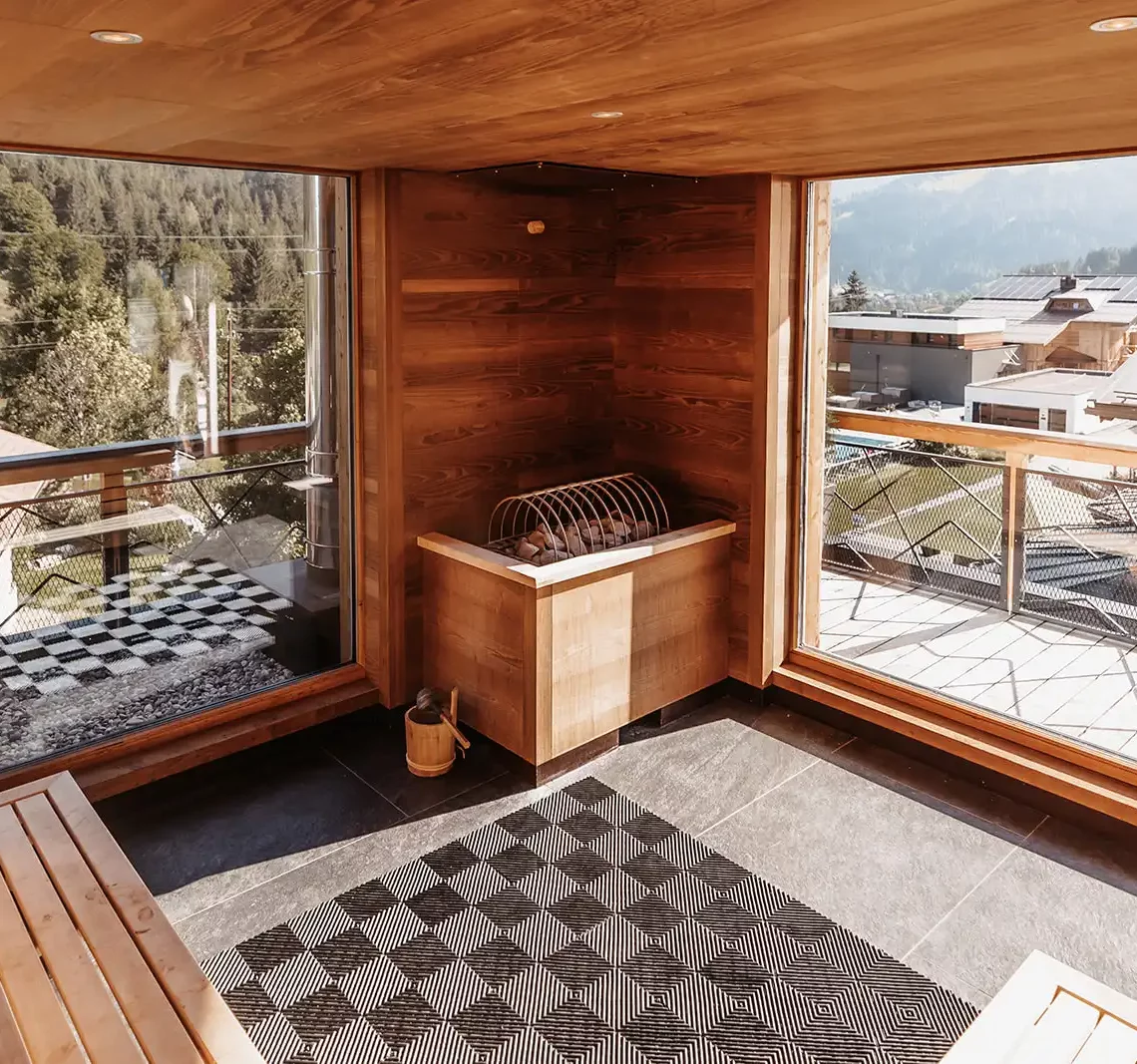 Moderne Sauna mit großen Fenstern und Blick auf die umliegende Berglandschaft.