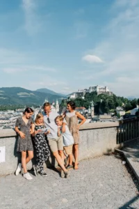 Familie mit Stadtplan genießt den Ausblick über Salzburg und die Festung Hohensalzburg im Sommer.