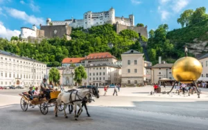 Kutsche auf dem Kapitelplatz mit Blick auf die Festung Hohensalzburg in Salzburg bei Sonnenschein.