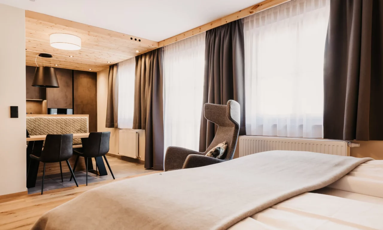 hofgut-apartment-lifestyle-resort-31 Helles Apartment mit gemütlichem Lesesessel, großem Bett und moderner Essecke – ideal für entspannte Stunden im Urlaub.