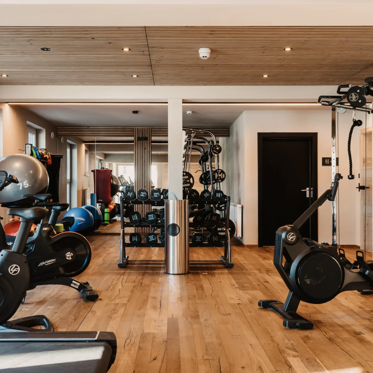 Vielseitig trainieren im stilvollen Fitnessbereich des Hofgut Wagrain – mit modernen Geräten, Freihanteln und Raum für Ihre persönliche Auszeit.