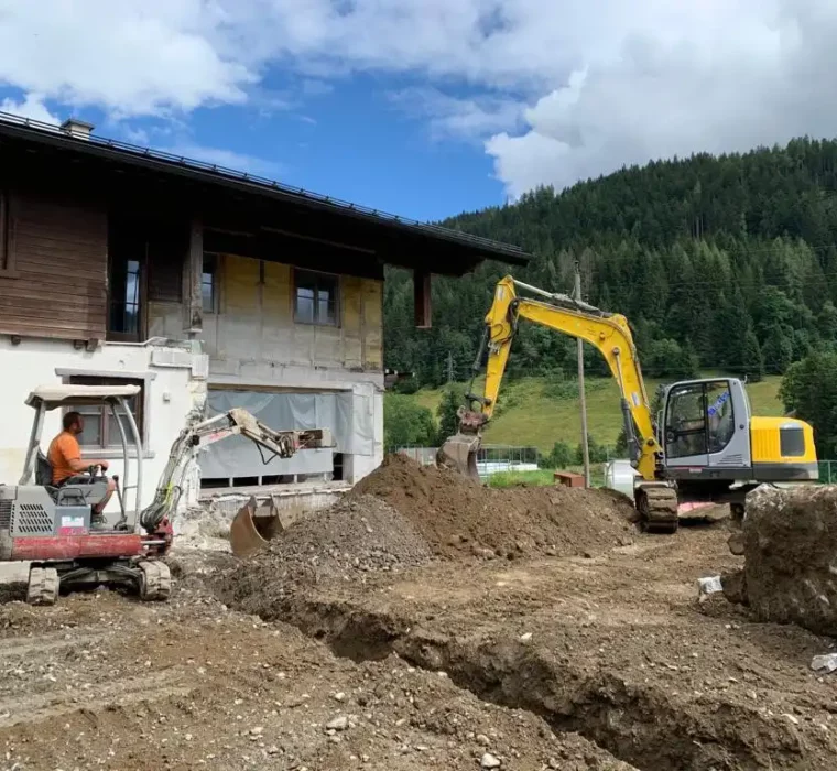 HOFGUT-apartment-lifestyle-resort-geschichte-umbau-lärchenhof Excavation work on the existing Hofgut Wagrain building against a green mountain backdrop