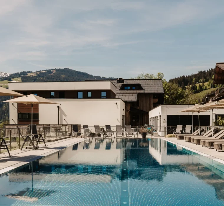 Hofgut-Wagrain-Apartment-Lifestyle-Resort-Wagrain 413 25-Meter-Sportbecken im Hofgut Wagrain mit Sonnenliegen und Schirmen – Sommerliche Ruheoase mit Bergblick für aktive und entspannte Urlaubstage im Salzburger Land.