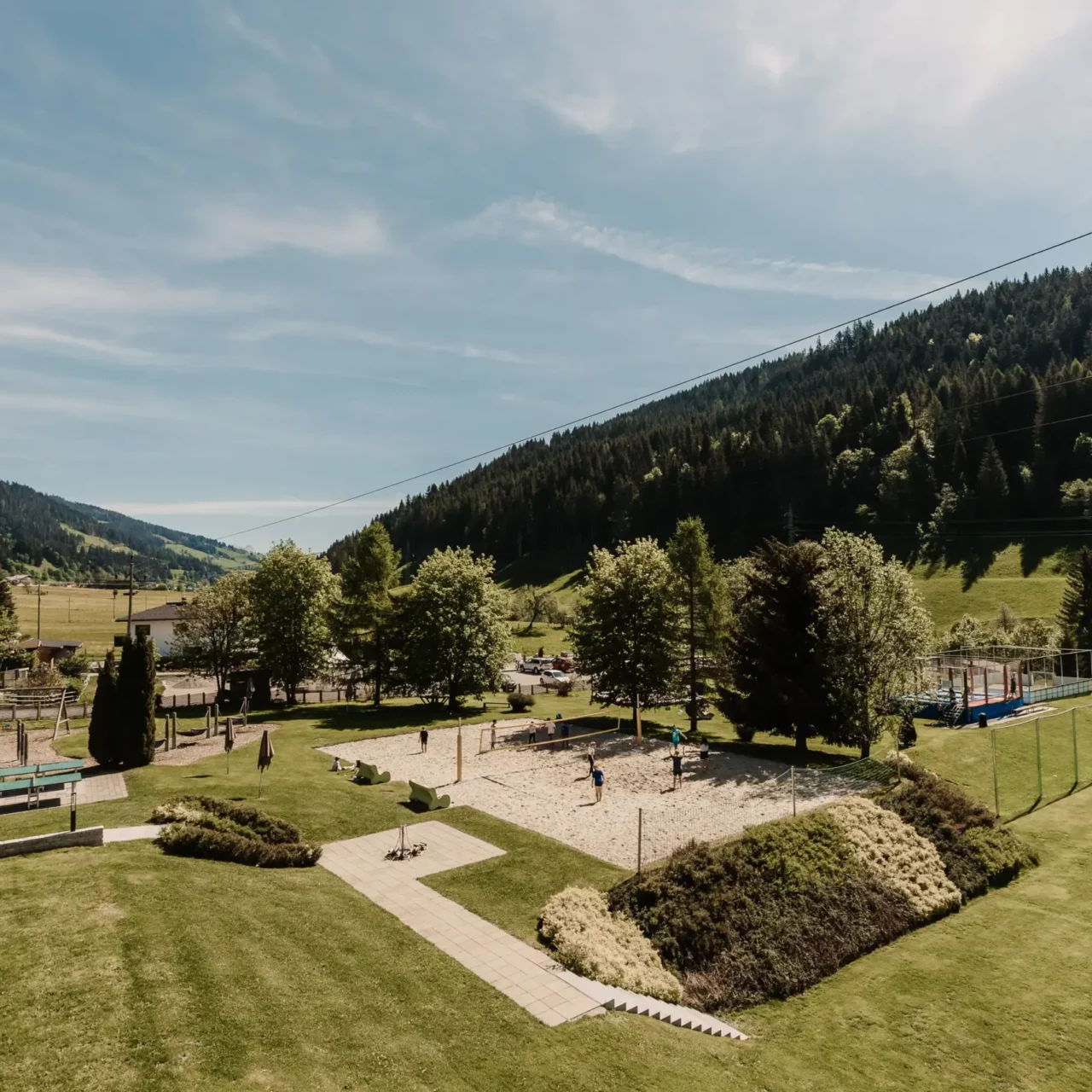 Varied summer garden area at Hofgut Wagrain - with playground, beach volleyball court, trampoline park and football pitch for active family moments in the middle of the Salzburg mountains.